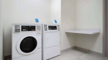 A laundry area with two front-loading washing machines and a white shelf.