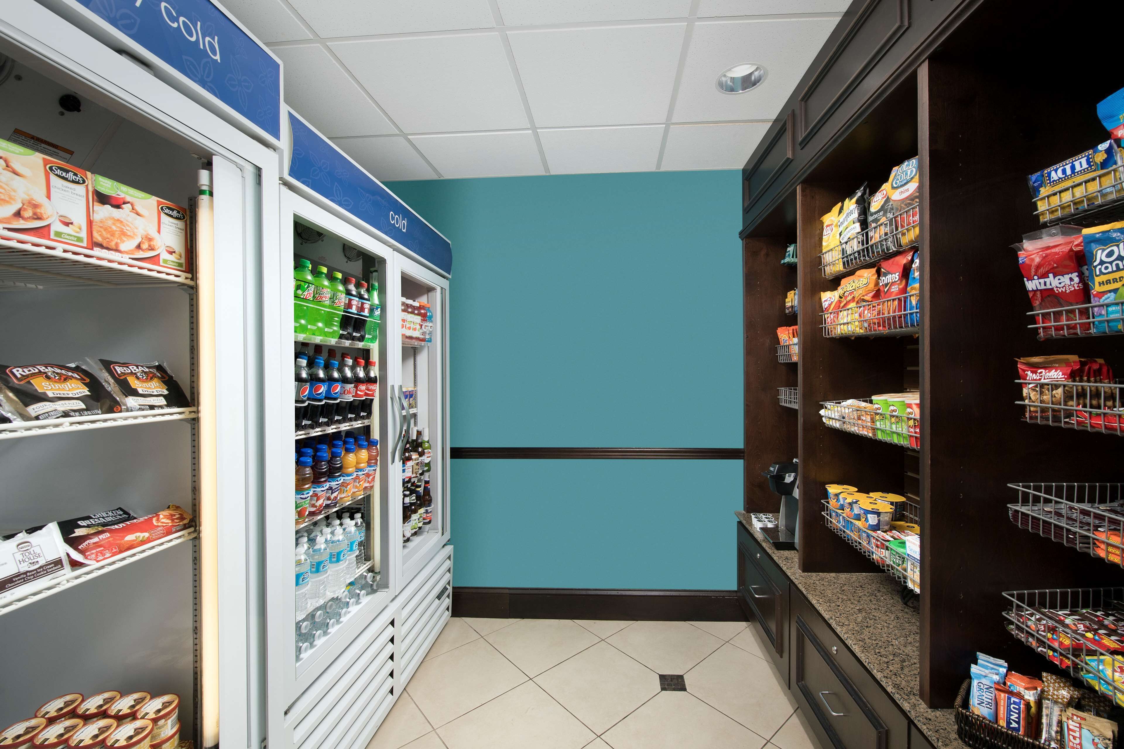 A grocery store interior with refrigerated sections on the left and shelves stocked with snacks and beverages on the right.