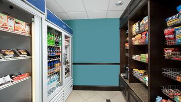 A grocery store interior with refrigerated sections on the left and shelves stocked with snacks and beverages on the right.