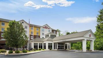 Un hôtel à plusieurs étages, avec un ciel dégagé et un espace d’entrée abrité.