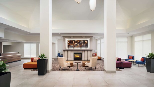 Een ruime lobby met een open haard, zithoek en moderne verlichting.