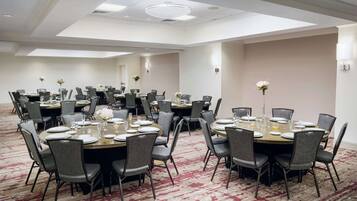 A conference room with multiple round tables, each set with chairs, plates, and glasses.