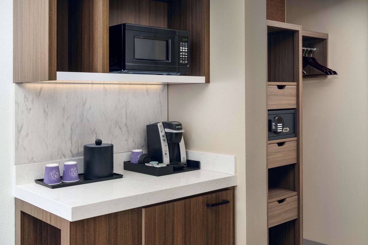 Eine moderne Küche mit integriertem Mikrowellenherd, Kaffeemaschine und Stauraumschubladen.