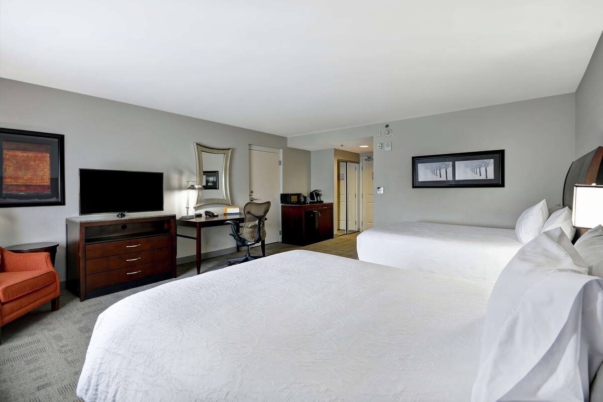 A hotel room with a large bed, a desk with a chair, a television, and a coffee machine.