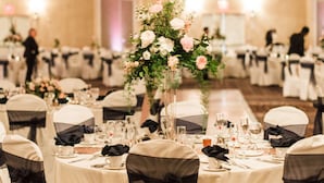 A banquet hall with round tables, white tablecloths, and black sashes on chairs. - Hilton Garden Inn Toledo Perrysburg (Perrysburg)