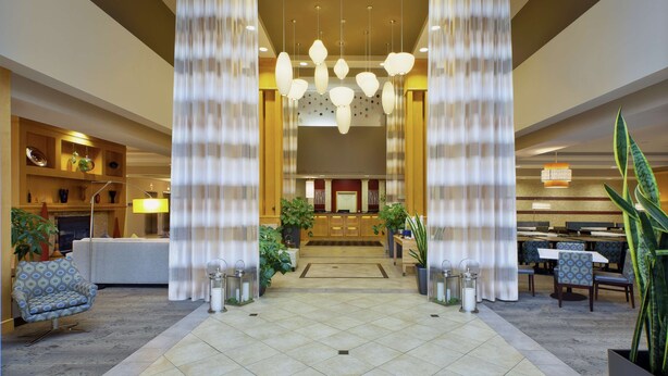 A spacious lobby with a reception desk, seating area, and modern lighting fixtures. - Hilton Garden Inn Toledo Perrysburg (Perrysburg)