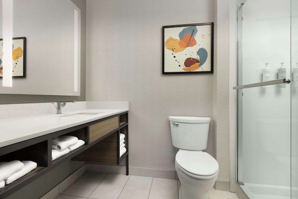 Une salle de bain moderne avec un lavabo blanc, des toilettes et une douche à parois de verre.