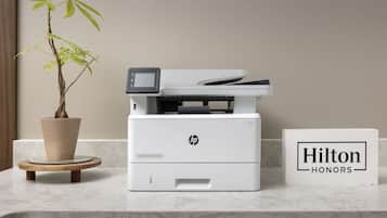 A printer on a marble countertop with a potted plant and a sign reading "Hilton Honors".