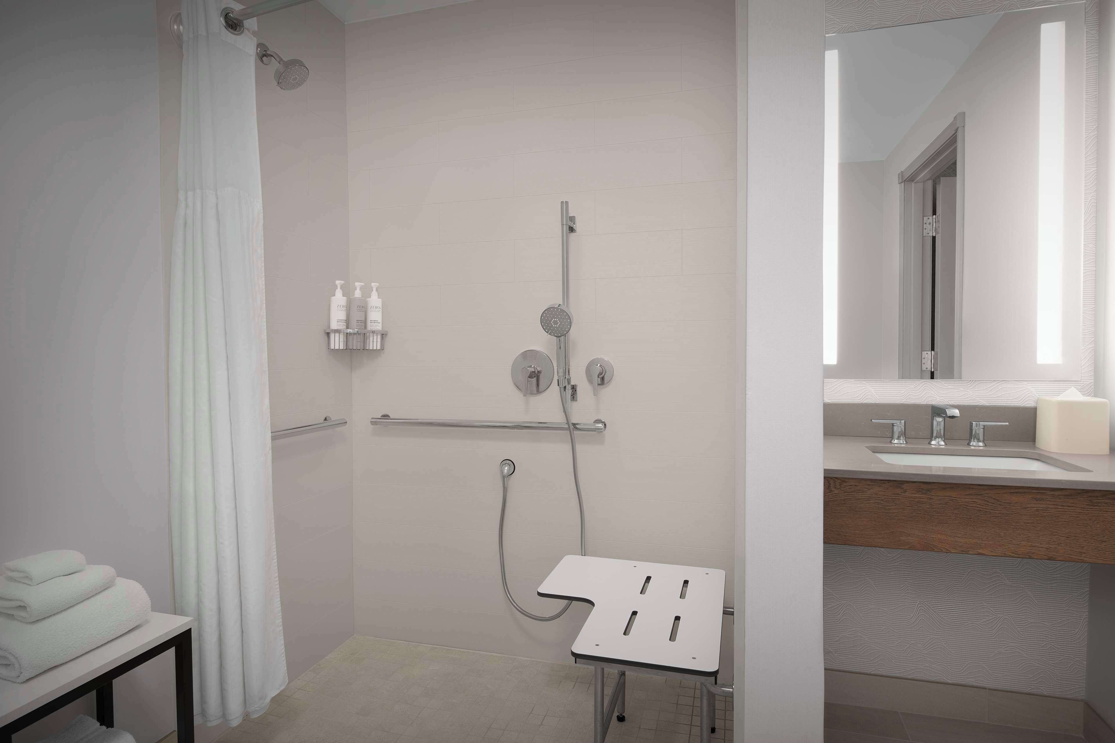 Un baño moderno con ducha, lavamanos y espejo.