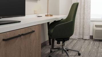 A modern office desk with a flat-screen monitor, a desk lamp, and a green office chair.