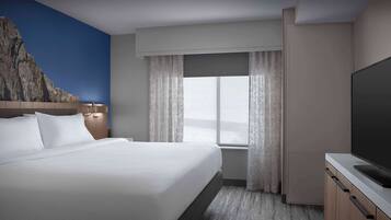 A hotel room with a large bed, a flat-screen TV, a window with curtains, and a wall mural.