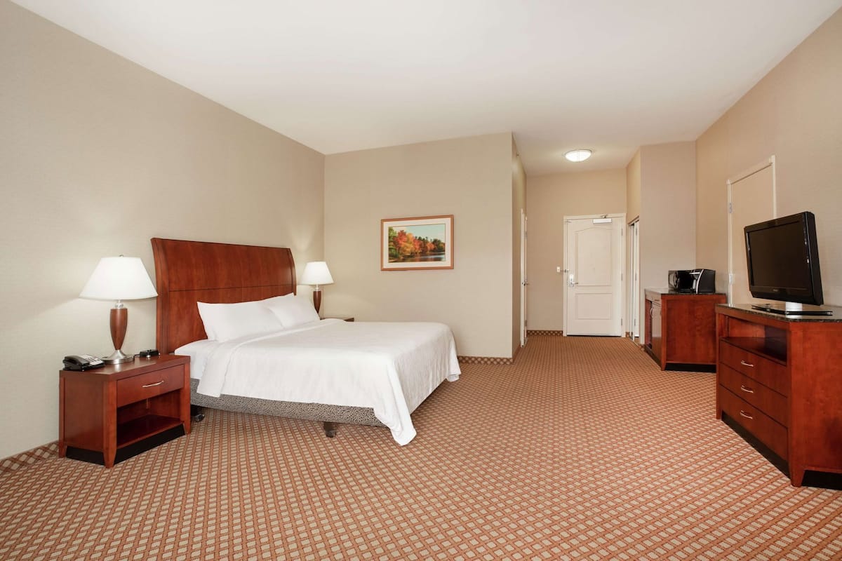 Ein Hotelzimmer mit Bett, Nachttischen, Fernseher, Schreibtisch und einer Tür.