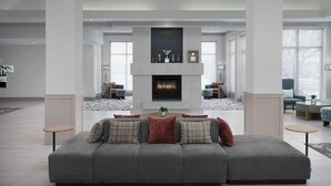 A modern living room with a fireplace, grey sofas, and a large window. - Hilton Garden Inn Casper (Casper)