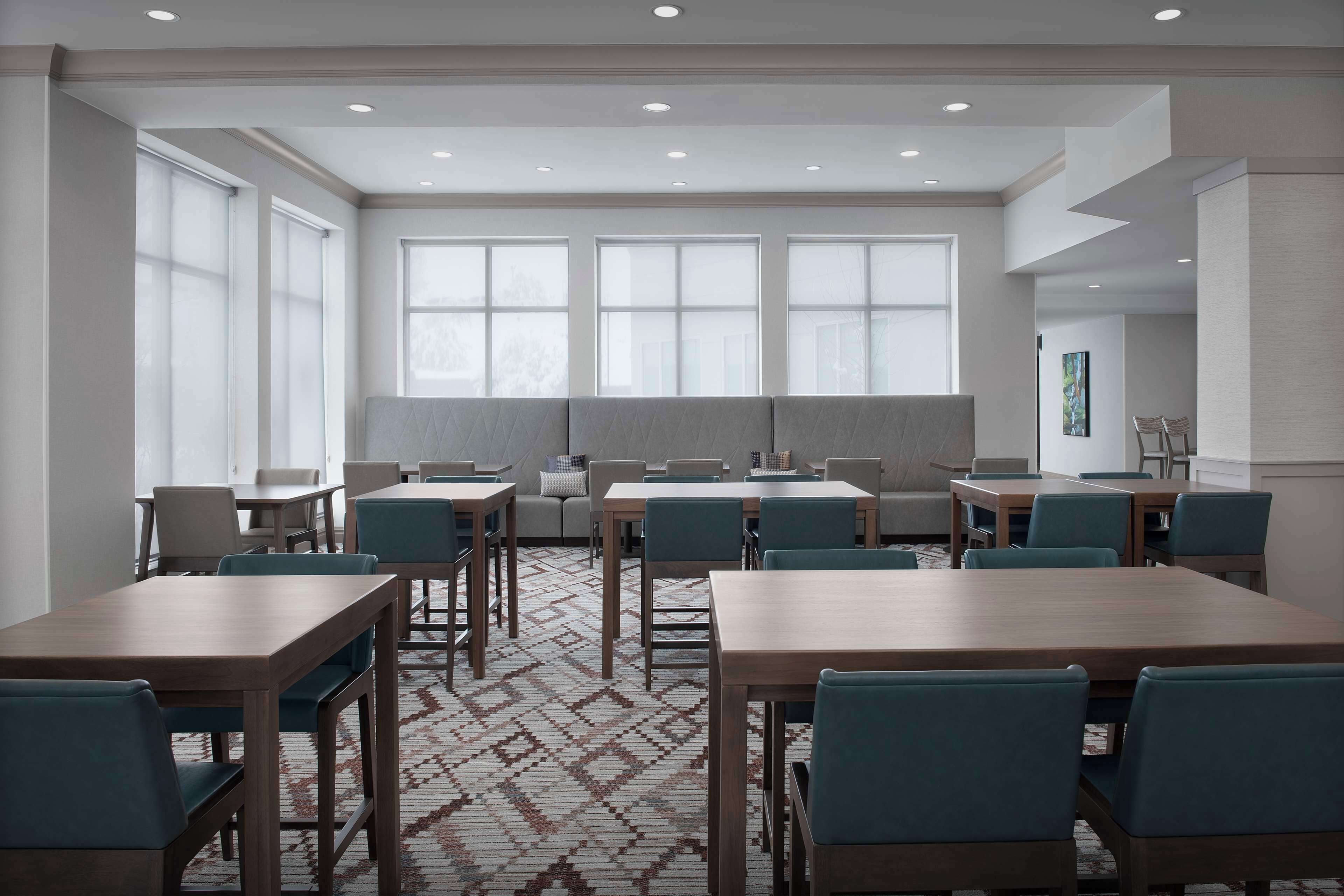 A conference room with multiple tables and chairs, large windows, and a patterned carpet.
