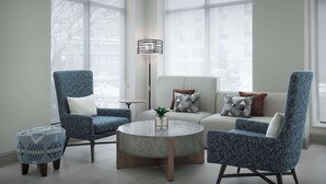 A modern living room with a blue armchair, a round coffee table, and a sofa with patterned cushions. - Hilton Garden Inn Casper (Casper)