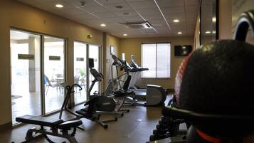 A gym with exercise equipment, large windows, and a ceiling with recessed lighting.
