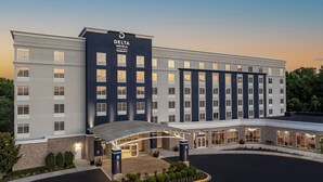 Un hotel moderno con fachada oscura, múltiples ventanales y una zona de acceso cubierta.