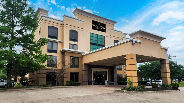 A hotel with a beige facade, a covered entrance, and a sign reading 'Country Inn & Suites.' - Country Inn & Suites by Radisson, Tyler University Area (Tyler)