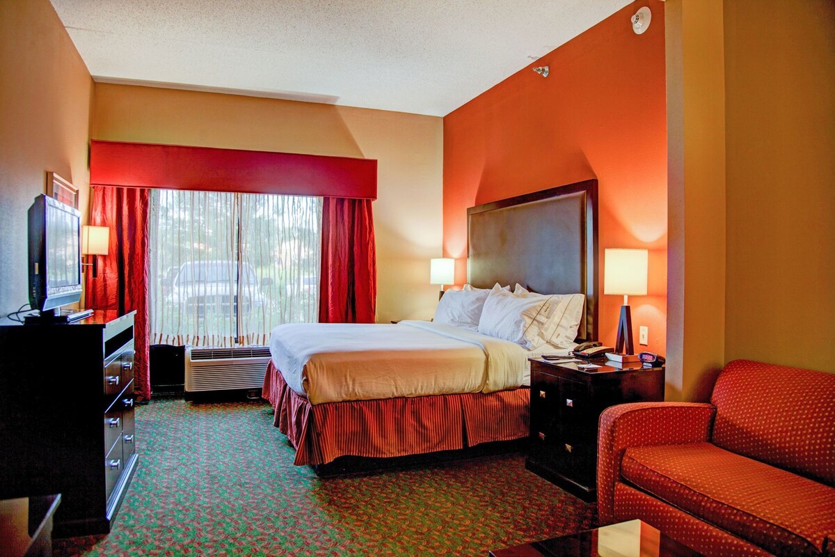 A hotel room with a bed, a desk, a chair, and a television.