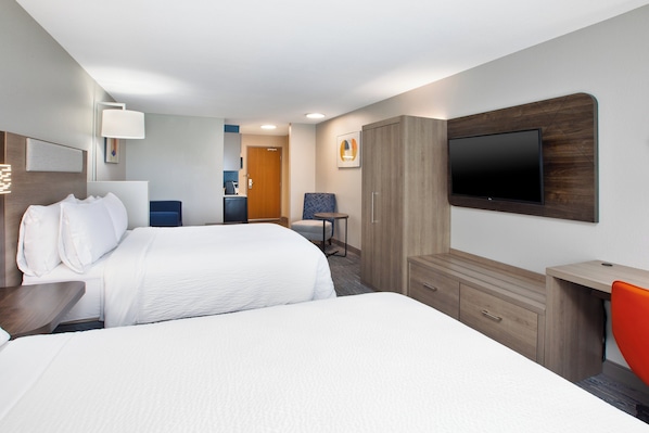 Une chambre d’hôtel avec deux lits, un bureau, une télévision et une armoire.