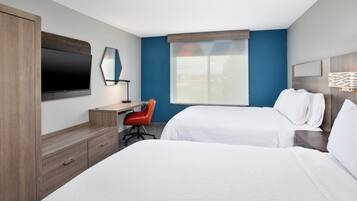 Habitación de hotel con dos camas, un escritorio, una silla, un televisor y una ventana con vistas.