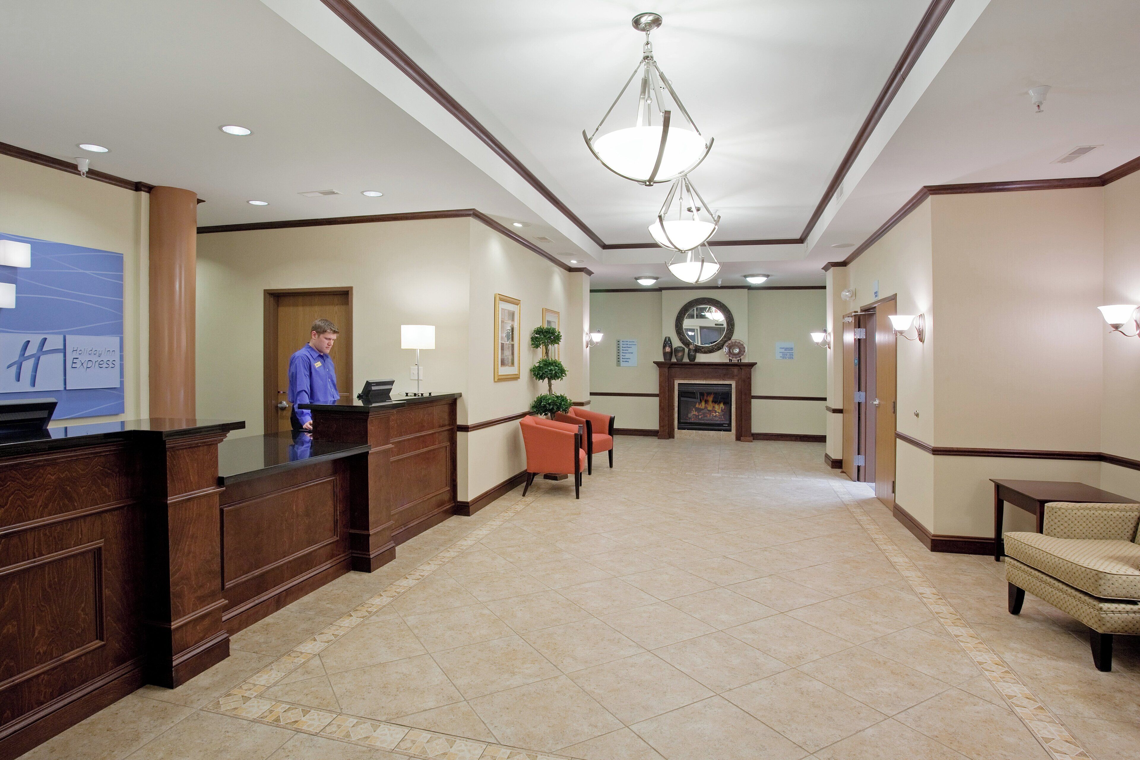 A hotel lobby with a reception desk, a fireplace, and a chandelier.