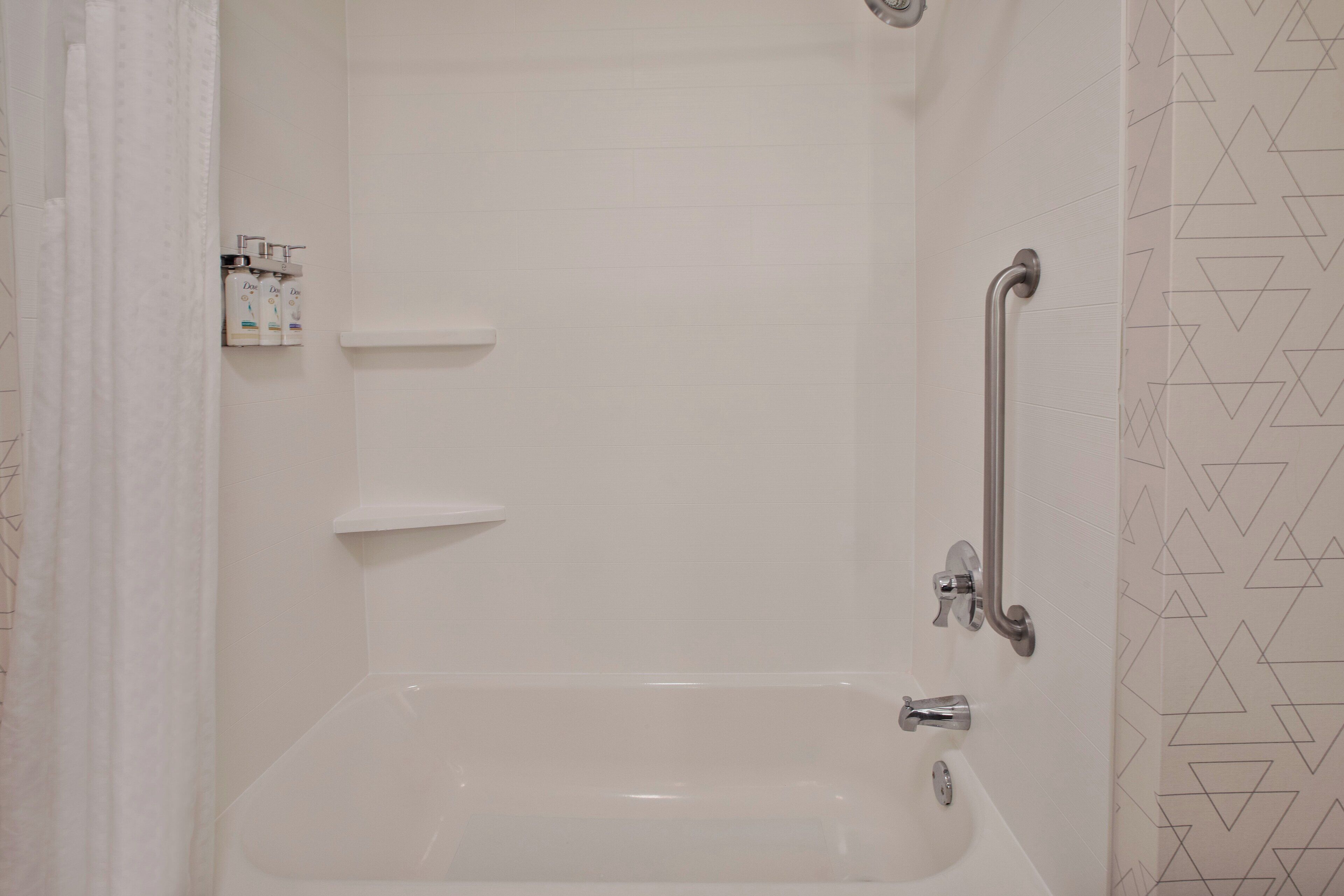 A bathroom with a bathtub, a shower, and a handrail.