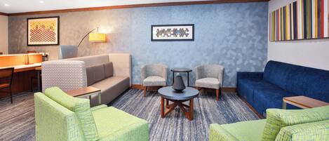 Un moderno vestíbulo de hotel con una zona de estar, un mostrador de recepción y una estación de café.