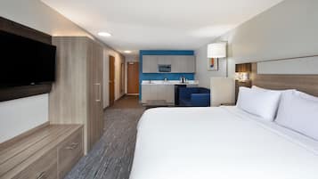 Habitación de hotel con una cama grande, un televisor de pantalla plana, una kitchenette y un baño.