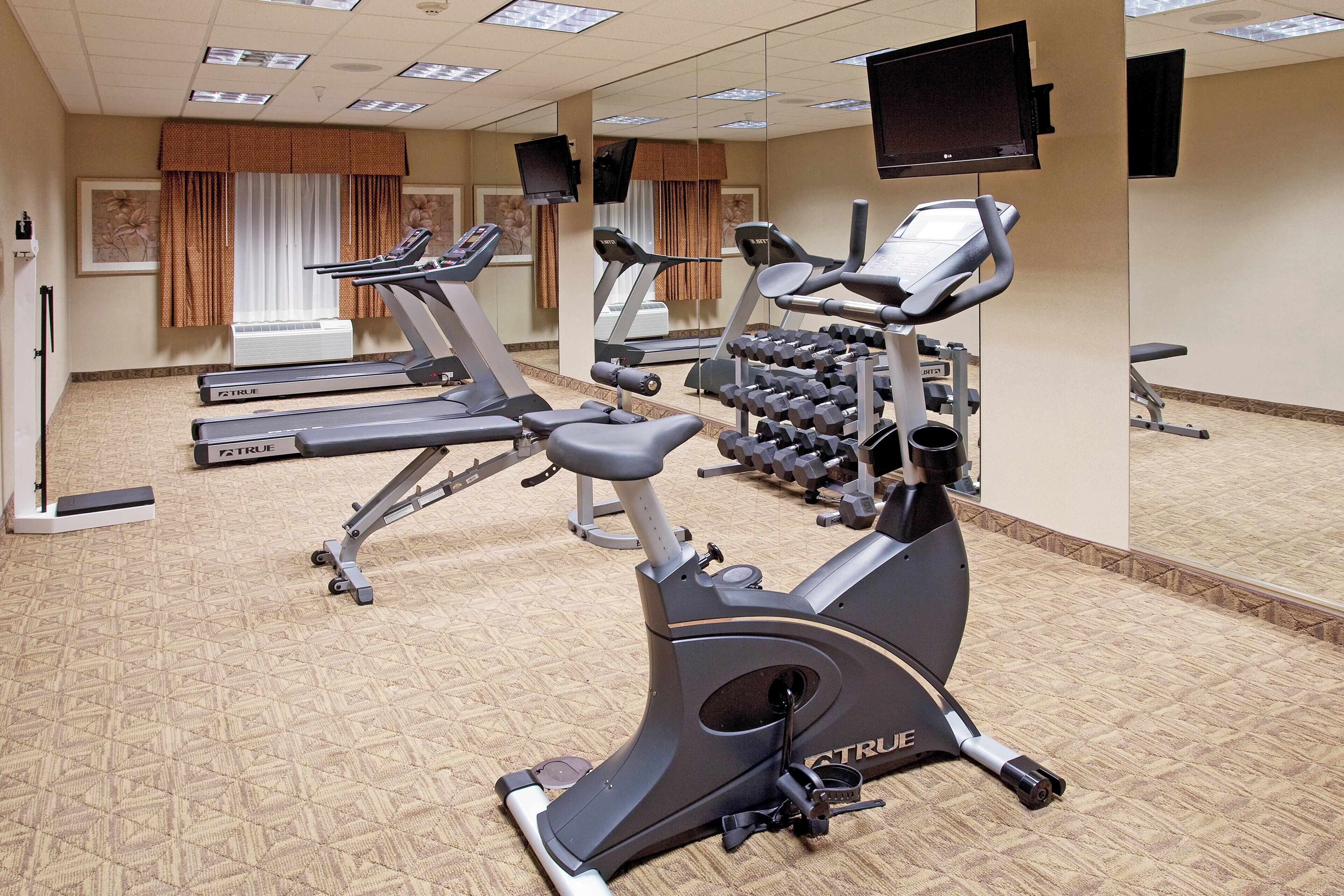 A gym with treadmills, an elliptical, and a rack of dumbbells.
