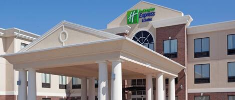Un hotel con entrada cubierta, fachada de ladrillo y un letrero que dice 'Holiday Inn Express & Suites'.