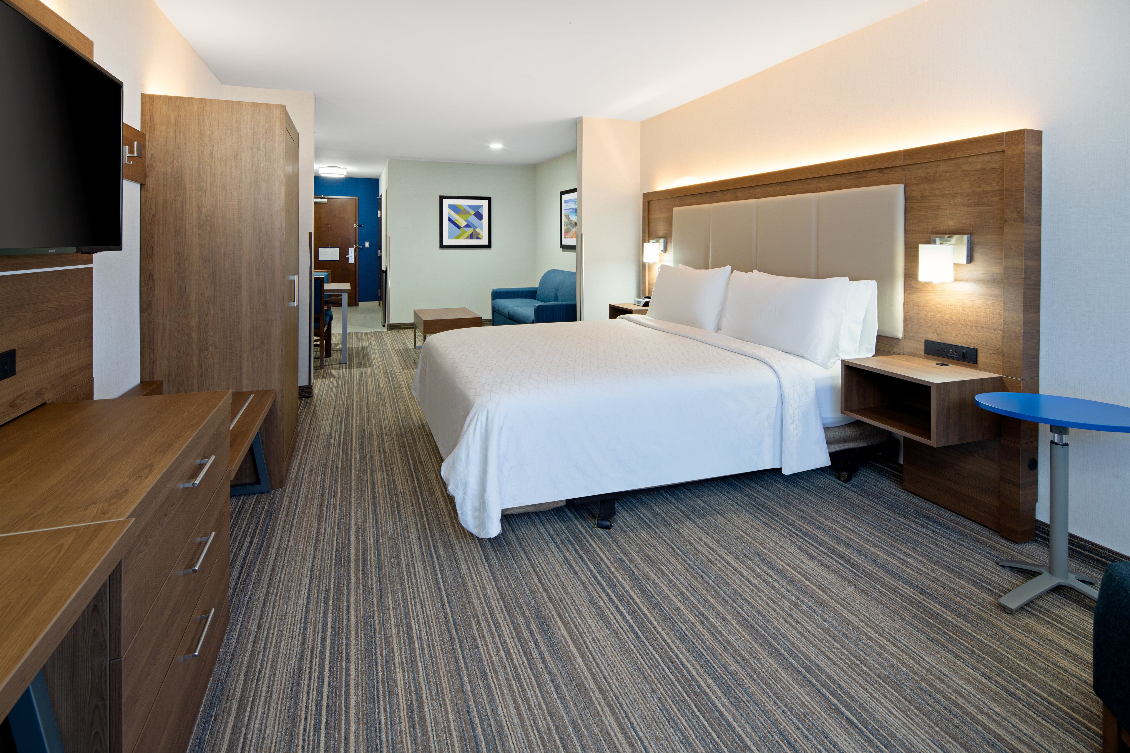 Une chambre d’hôtel avec un grand lit, un bureau, une chaise, une télévision et une petite table.