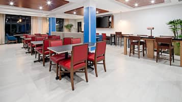 A modern dining area with red and brown chairs, wooden tables, and a blue pillar.