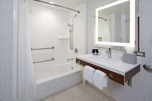 A modern bathroom with a bathtub, a vanity with a mirror, and a shower area.