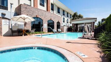Relax by the pool surrounded by comfortable lounge chairs and umbrellas, with a covered seating area nearby.