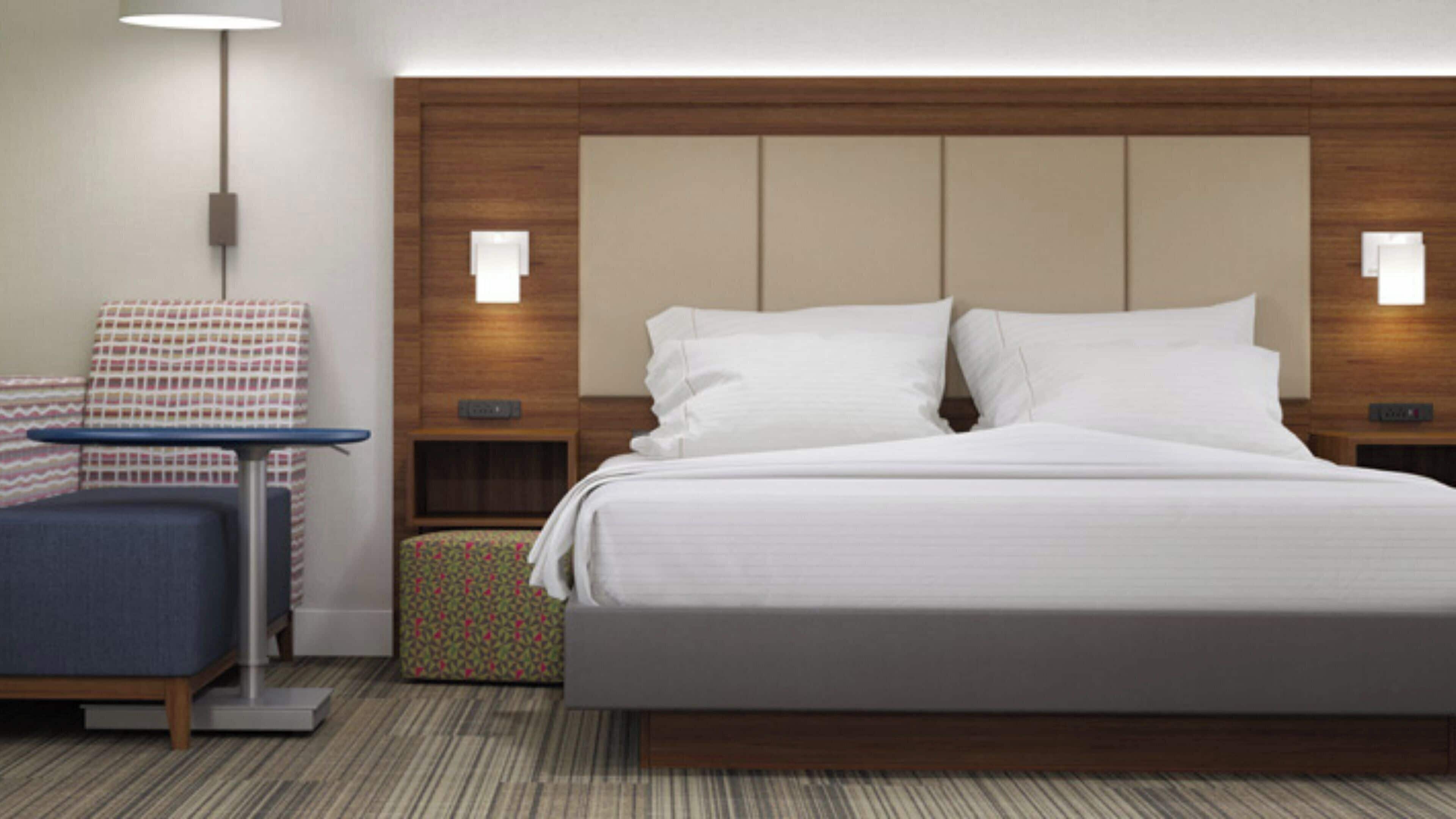 A hotel room with a large bed, bedside tables, a desk, and a chair.