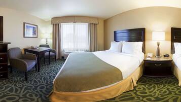 A hotel room with a large bed, a desk, a chair, a lamp, and a window with curtains.