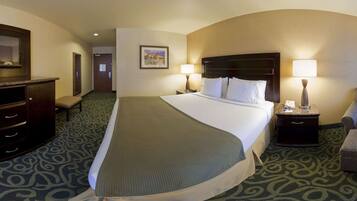 A hotel room with a large bed, two bedside tables with lamps, a dresser, and a carpeted floor.