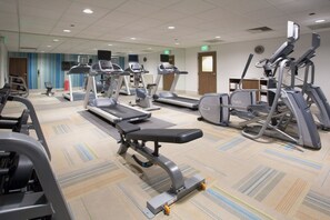 A gym with treadmills, elliptical machines, and weight benches.