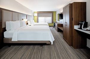 Habitación de hotel con una cama grande, un escritorio con cafetera, televisor y ventana con vistas.