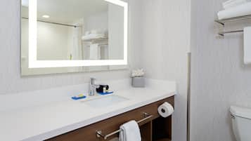 A modern bathroom with a large mirror, white sink, and a toilet.