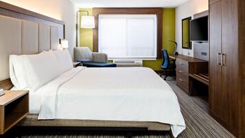 A hotel room with a large bed, a desk with a chair, a television, and a wardrobe.