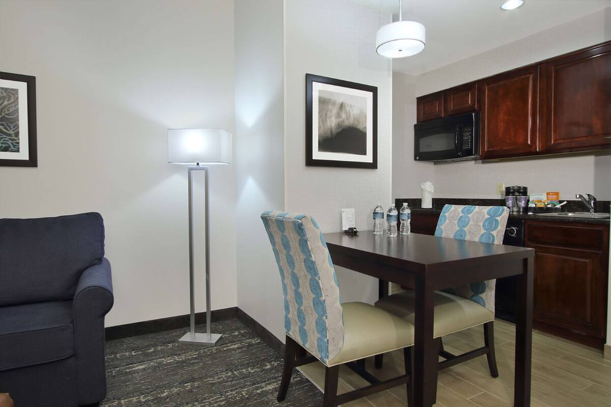 A modern kitchen with dark wooden cabinets, a microwave, and a dining area with a table and chairs.