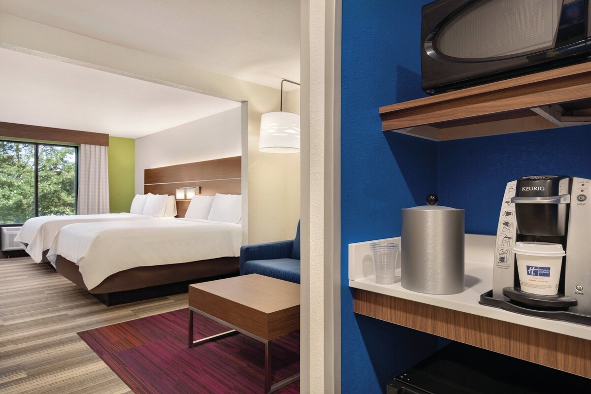 A hotel room with two beds, a sofa, a coffee maker, and a microwave.
