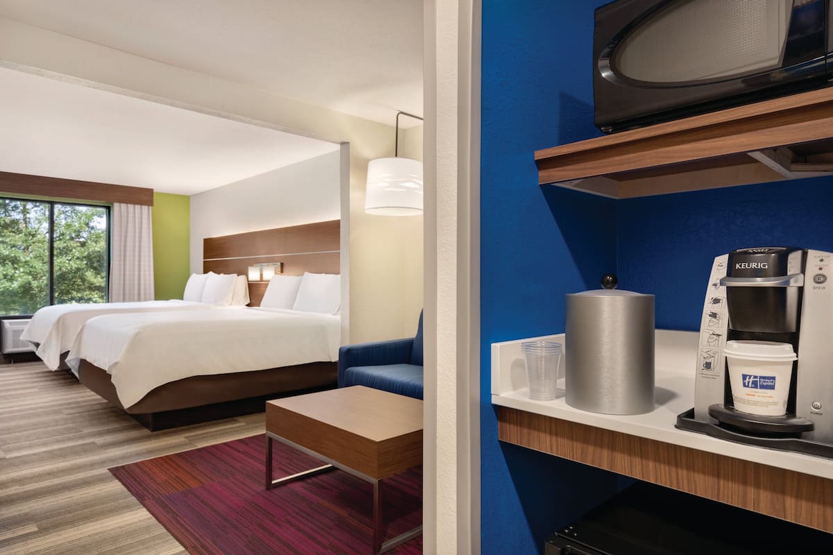 A hotel room with two beds, a sofa, a coffee maker, and a microwave.