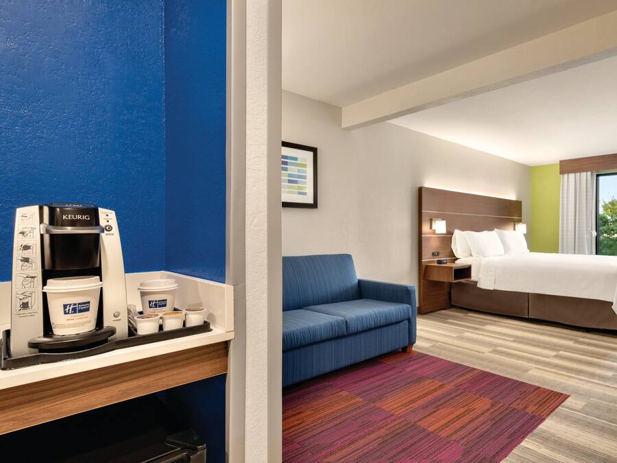 A hotel room with a bed, a sofa, a coffee machine, and a window with a view.