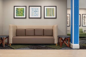 A hotel lobby with a brown sofa, two side tables, and three framed artworks on the wall. - Holiday Inn Express Hotel & Suites Lavonia by IHG (Lavonia)