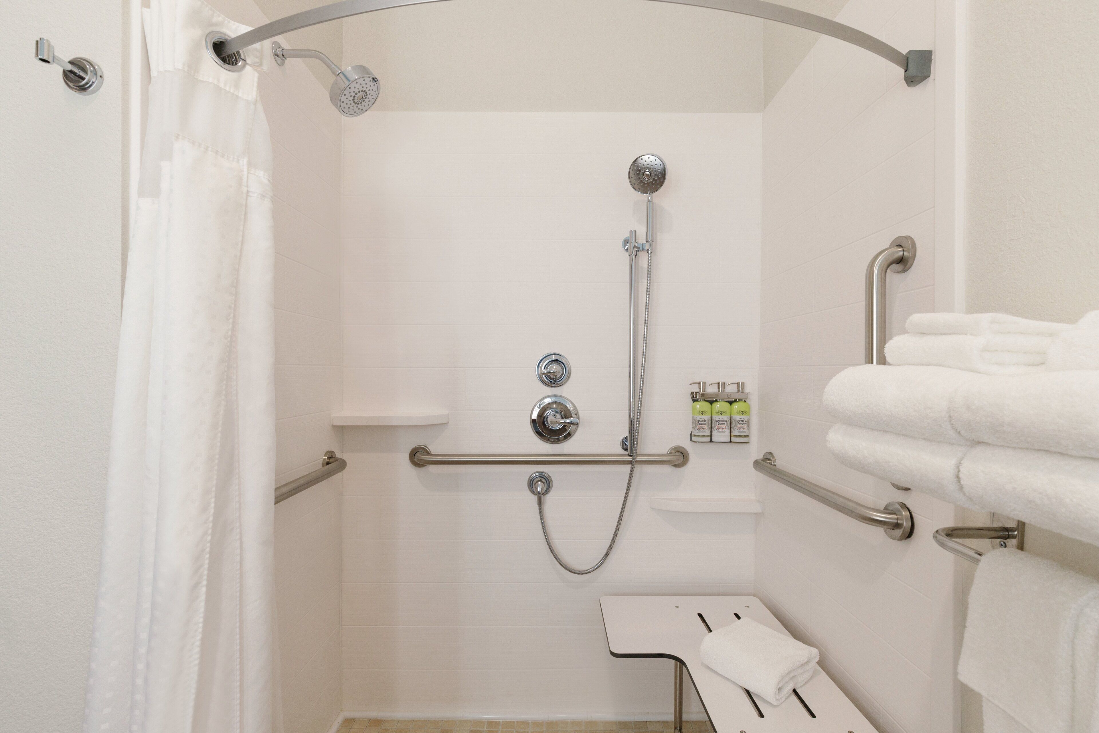 Un espace douche équipé d’une barre d’appui, d’une étagère pour les articles de toilette et d’un porte-serviettes.