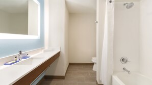 Un baño con lavamanos blanco, espejo y ducha.