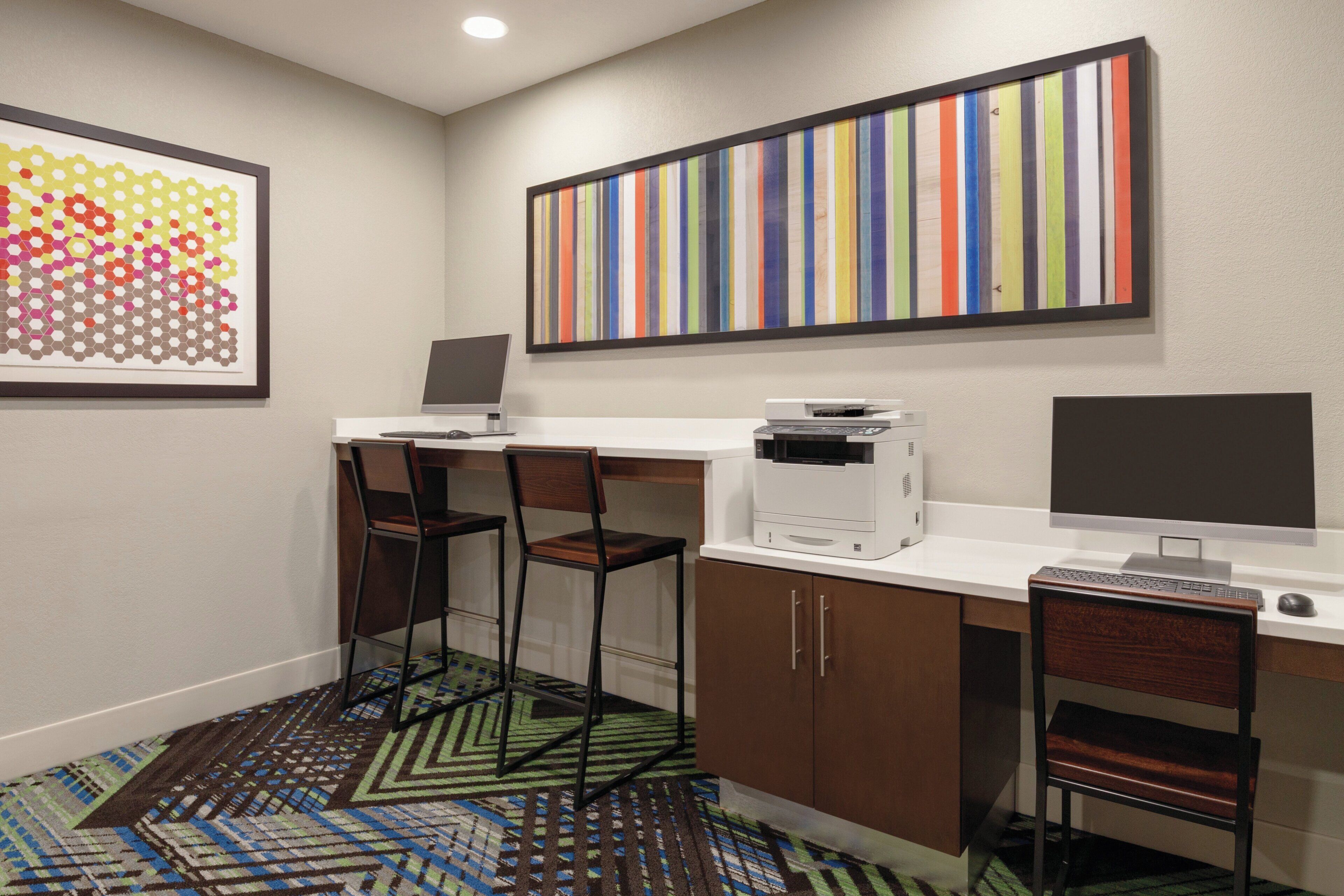 A small office space with a desk, two chairs, a printer, and a computer monitor.